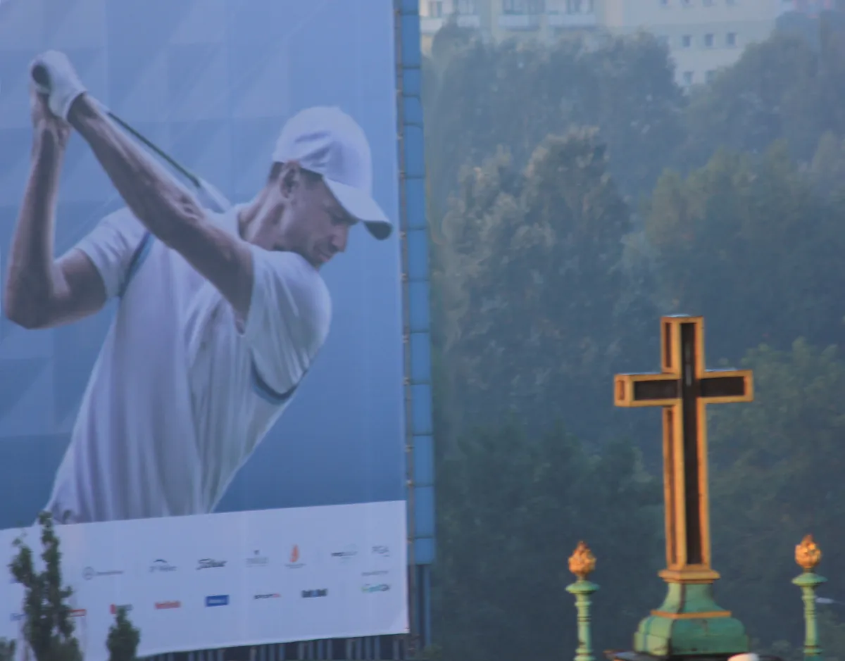Large golfer billboard rising beside a church cross
